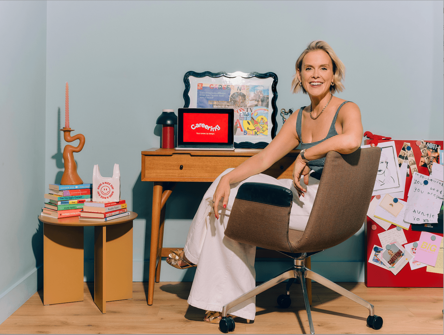 Lauren sitting at her desk, smiling and facing the camera. Her laptop is open.